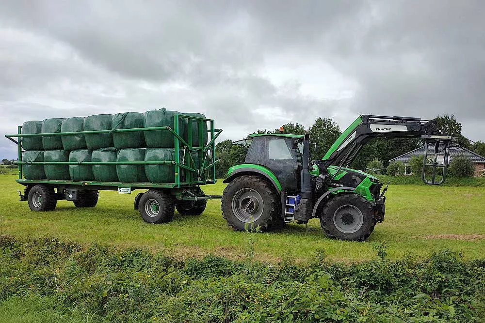 Trecker mit vollbeladenen Hänger mit hochwertigem Futter auf der Weide