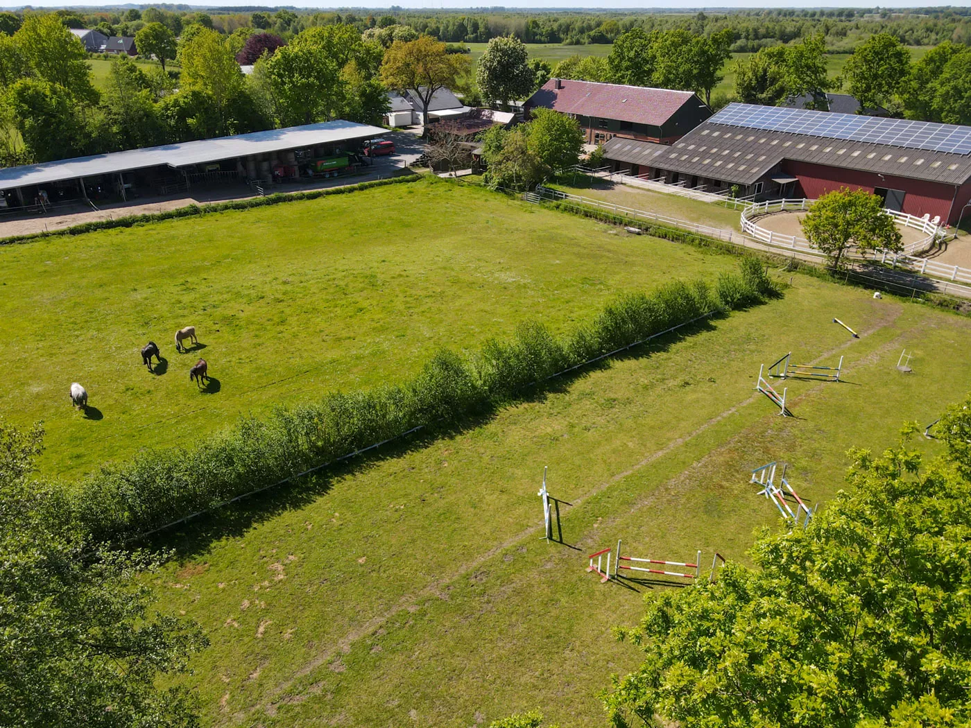 Unser Hof und die Weiden mit Pferden dahinter aus der Vogelperspektive